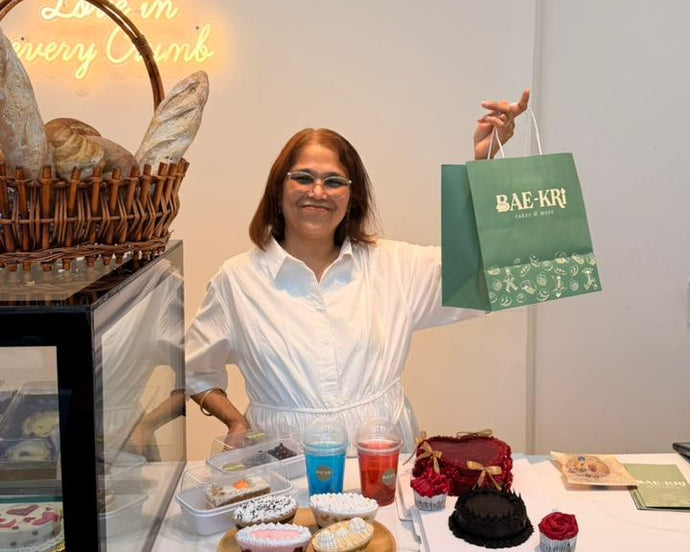 Person holding a green bag in front of a display of pastries and drinks.


